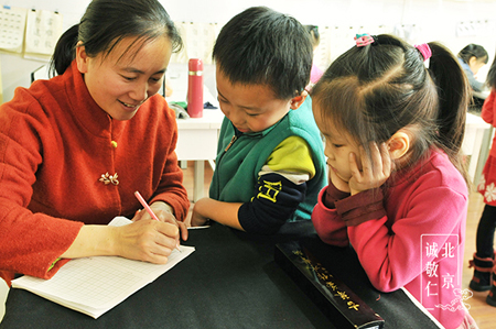 幼兒班的小同學在周老師的指導下學習硬筆字